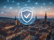 Öffentliche Einrichtungen Luftaufnahme einer europäischen Altstadt bei Sonnenuntergang, mit historischen Gebäuden und Kirchen. Über der Stadt verlaufen leuchtende Verbindungslinien, die ein digitales Netzwerk symbolisieren. Im Vordergrund schwebt eine transparente Schutzblase mit einem Häkchen, die Sicherheit und gesetzeskonformen Schutz visualisiert.