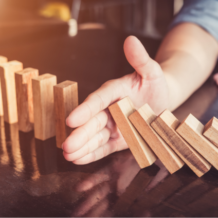 Tool overload: Too many programmes, no integration and rising costs Hand stops falling dominoes - symbolising too many individual solutions and a lack of system integration.